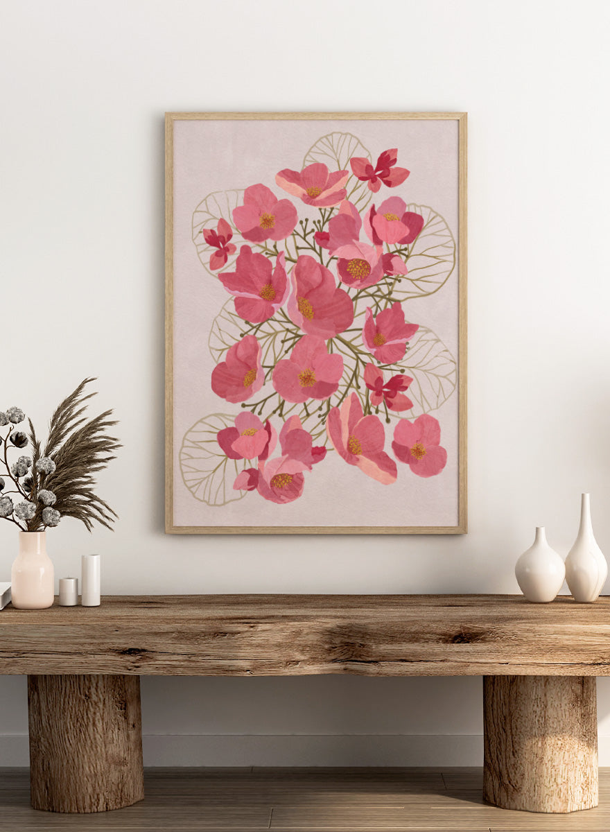 A framed botanical art print featuring pink flowers with yellow centers and delicate gold leaf outlines on a pale pink background. Shop Japanese Quince Floral Art Print by Katie O&