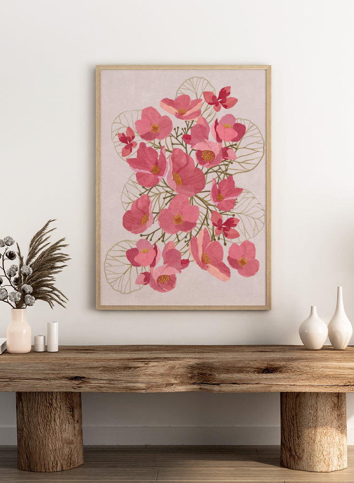 A framed botanical art print featuring pink flowers with yellow centers and delicate gold leaf outlines on a pale pink background. Shop Japanese Quince Floral Art Print by Katie O&