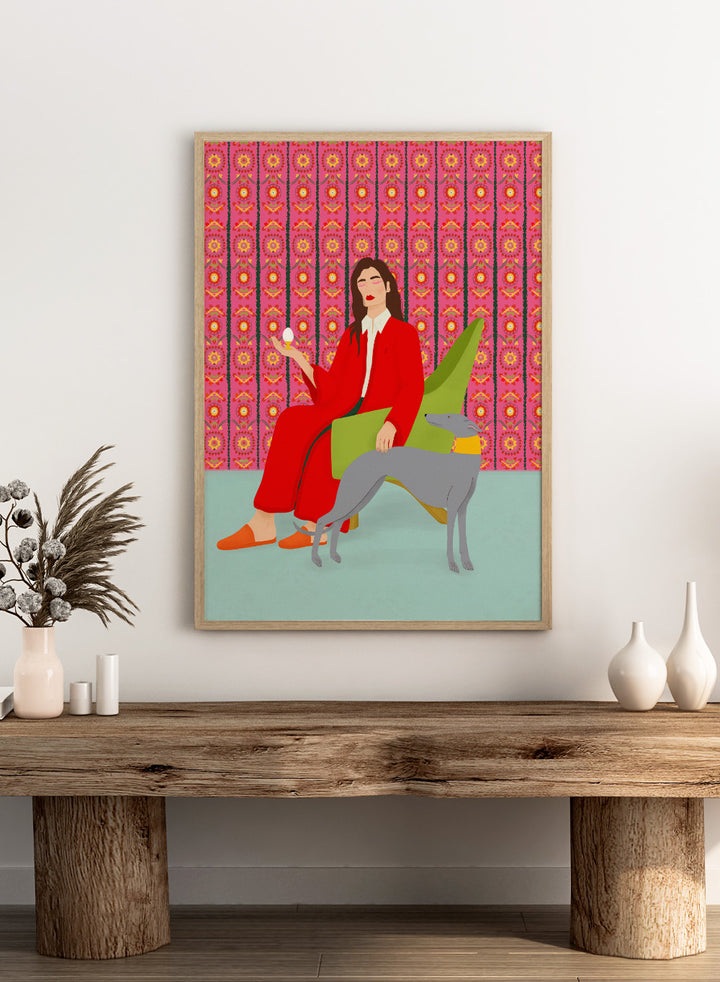 Woman in a red coat sitting on a green chair with a dog, against a pink patterned wall. Wonderful Egg by Jota de Jai is a whimsical modern art print of a woman in a red robe holding an egg with her greyhound, officially licensed wall poster with framing.