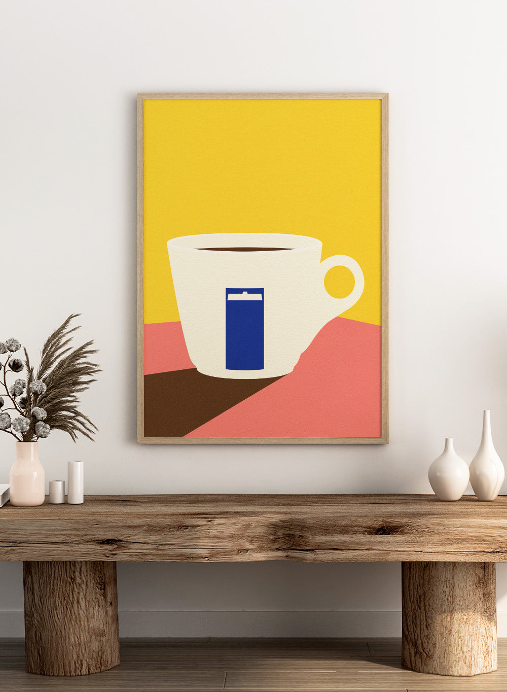 White coffee cup with a blue book design on a yellow and pink background. Tazza by Rosi Feist is a minimalist modern art print of a coffee cup in bold Bauhaus-inspired color blocks. Officially licensed fine art poster with framing.