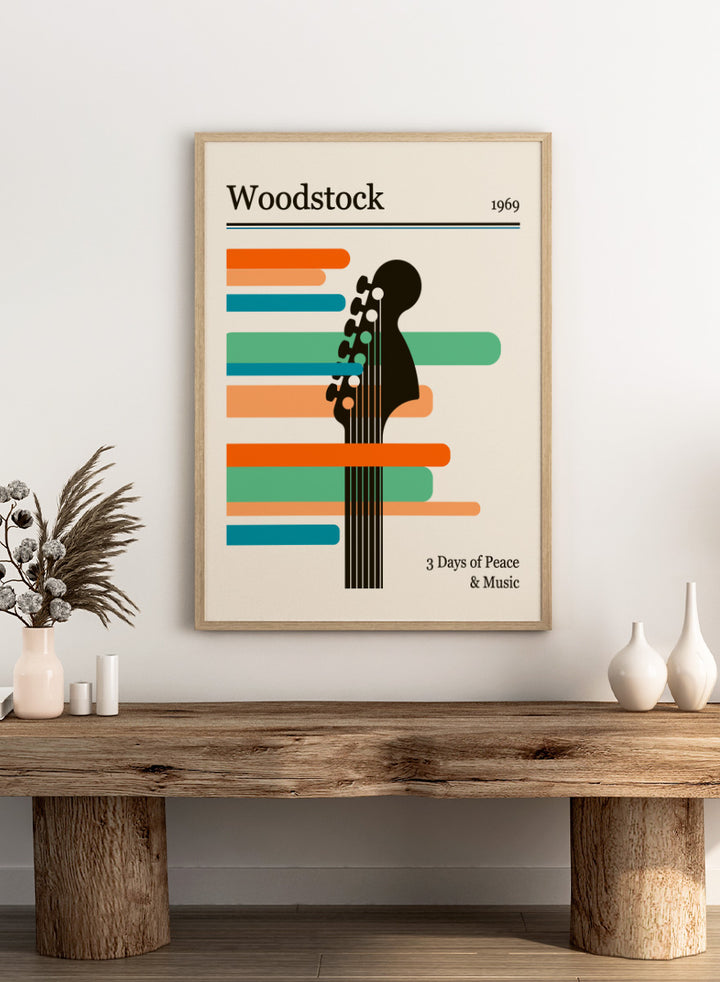 A graphic poster-style design for Woodstock 1969, featuring a black guitar headstock silhouette layered over horizontal orange, teal, and blue bars on a warm cream background. The text reads &