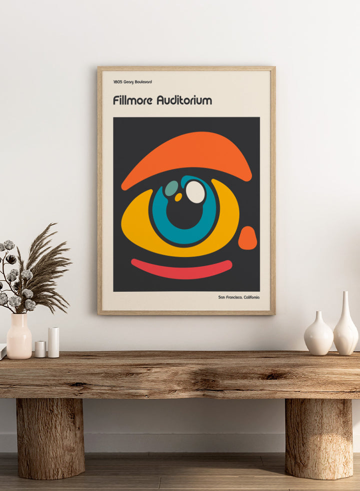 A poster-style graphic for the Fillmore Auditorium in San Francisco, California, featuring an abstract eye illustration in orange, yellow, blue, red, and white on a dark gray square, with cream margins and black text reading &