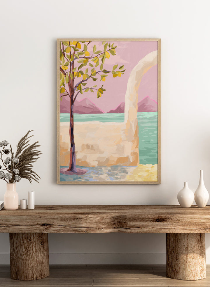 Artistic depiction of a tree by a lake with mountains in the background. Lemon Tree by Goed Blauw is a coastal art print and wall poster featuring a lemon tree, soft pastel sky, and ocean view in warm tones.