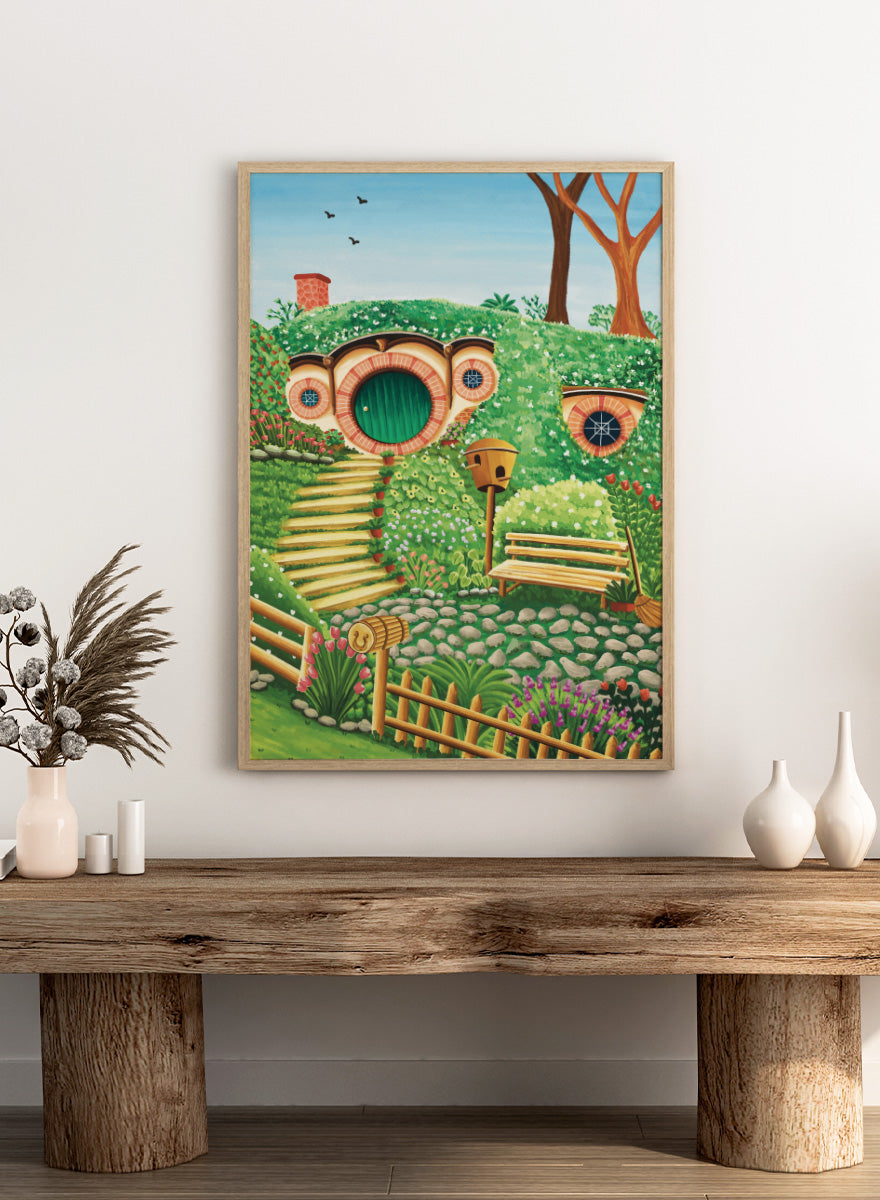 A colorful fantasy-style illustration of a hobbit hillside scene with a round green door, stone steps, flowers, trees, a bench, and a birdhouse under a blue sky. Shop Whimsical Hill House by Nidhi Kachhadiya, a colorful cottage wall art print featuring a garden home, lush greenery, flowers, and playful storybook details.