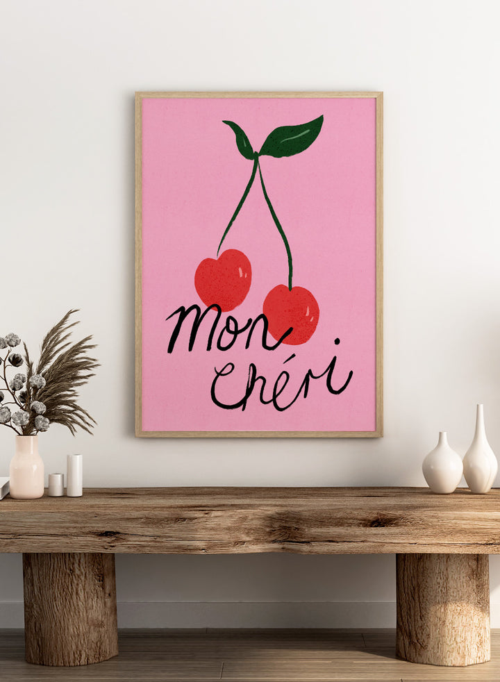 Two red cherries with green stems on a pink background and 'mon chéri' text. Mon Chéri by Dirkie Nell is a cherry typography art print featuring bold red fruit and playful lettering. A colorful love-inspired wall poster.