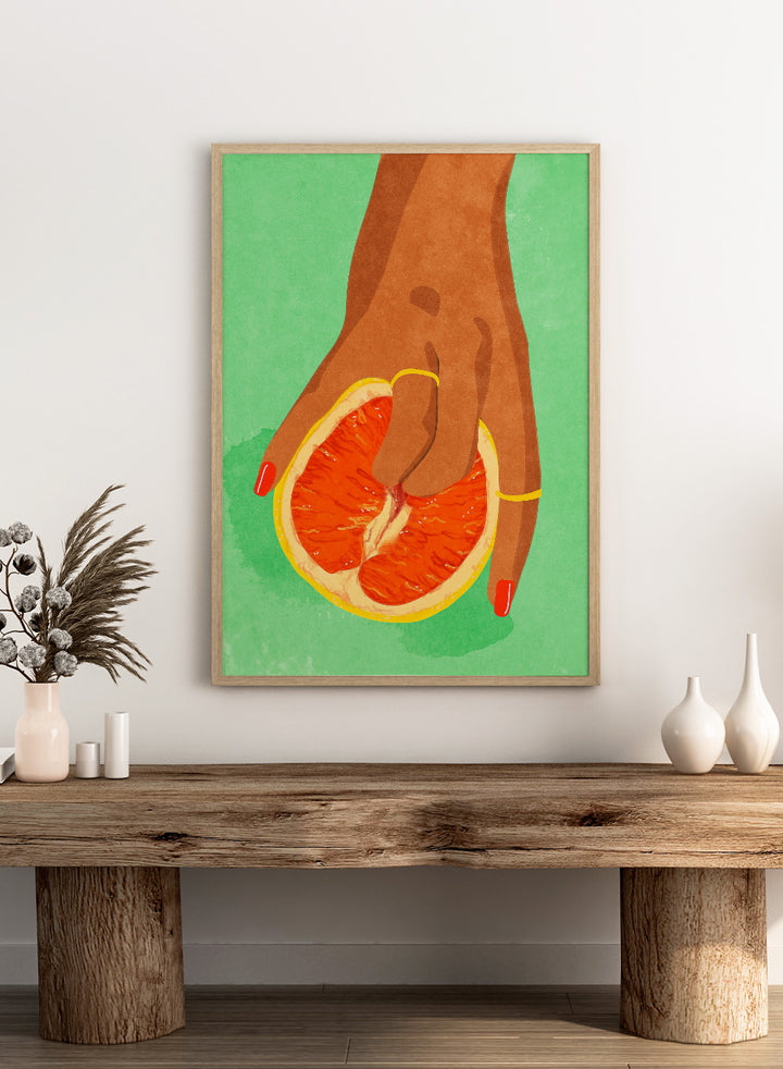 Illustration of a hand holding a sliced orange against a green background. Fruit Lover wall art print by Raissa Oltmanns blends playful citrus and intimate symbolism in a contemporary modern aesthetic poster.