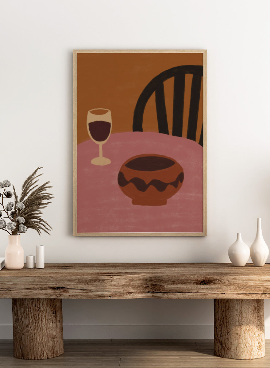 A stylized still life artwork showing a pink table, a dark brown bowl in the foreground, a wine glass with deep red liquid, and a black chair against a warm brown background. Warm Dining Still Life by The Art Concept still life art print featuring red wine, a rounded bowl, pink tabletop, and rich burgundy and rust tones.