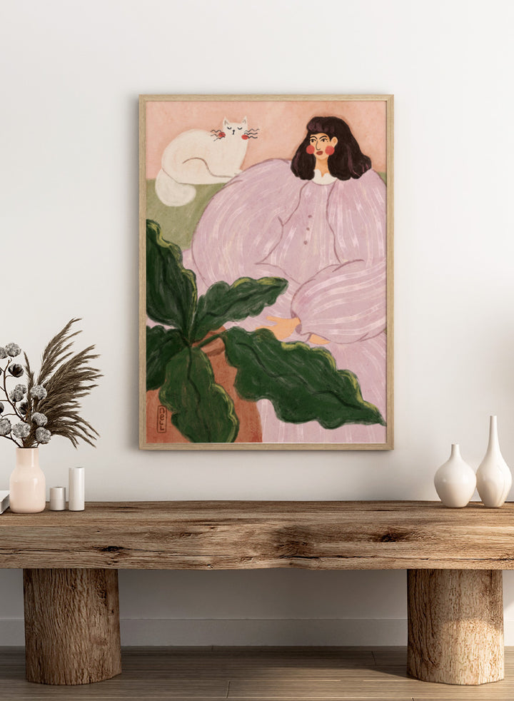 A stylized painting of a woman in a pale pink striped dress seated beside a white cat, with large green leaves in the foreground and a peach background. Cozy Woman With Cat by Dirkie Nell is a colorful portrait and animal art print featuring a woman in lavender, a white cat, oversized leaves, and soft pink tones.