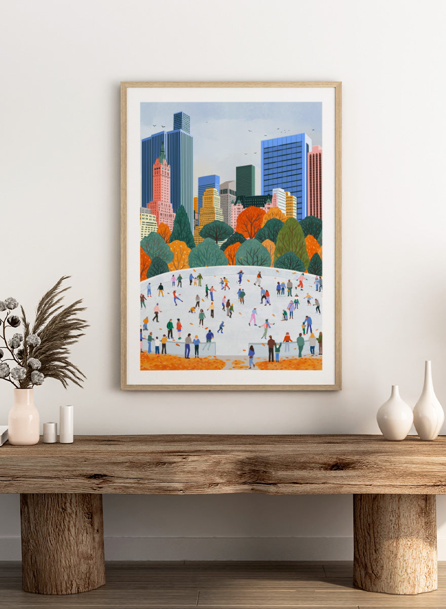 A framed art print depicting a city skyline with autumn trees and a large white ice rink filled with small illustrated people skating. Autumn City Ice Skating by Ceyda Alasar city art print featuring a lively outdoor rink, fall trees, skaters, and a colorful urban skyline.