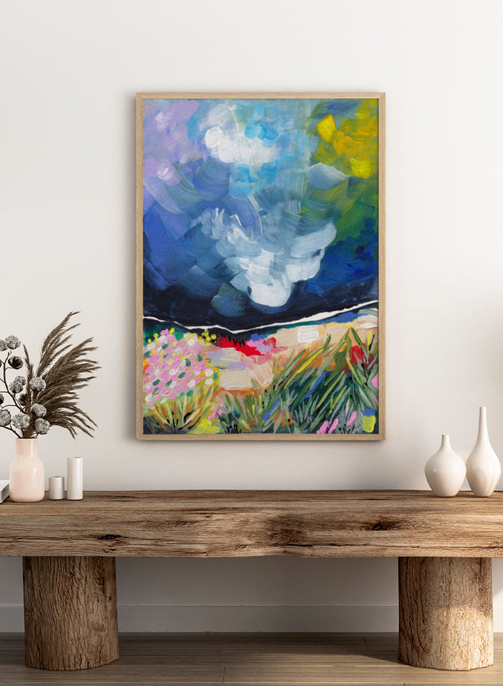 An expressive landscape painting featuring a dark blue stormy sky with swirling brushstrokes and a foreground of green grasses, pink flowers, and yellow-green foliage. Shop Vibrant Abstract Field Sky by Dirkie Nell, a colorful abstract landscape art print featuring wildflowers, open fields, and a dramatic blue sky.