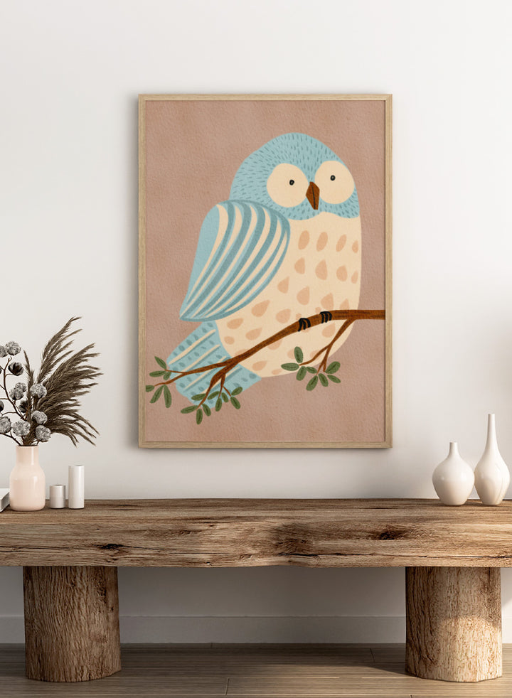 A stylized illustration of a blue and cream owl perched on a brown branch with green leaves, set against a warm beige background. Shop Whimsical Blue Owl by Nikita Jariwala, a blue owl wall art print poster for nursery and kids room decor featuring a playful bird illustration and soft blue tones.