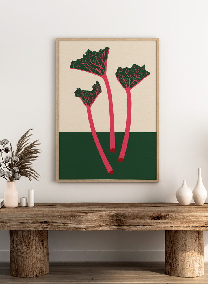 Illustration of red rhubarb stalks with green leaves on a beige and green background. Swedish Garden Rhubarb by Rosi Feist is a modern botanical art print with bold minimalist color and Bauhaus-inspired design. Officially licensed fine art poster with framing.