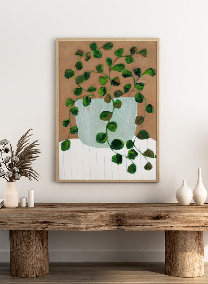 Shop Warm Houseplant Pot by Nikita Jariwala, a botanical wall art print poster featuring a trailing houseplant in a green pot with warm green tones.