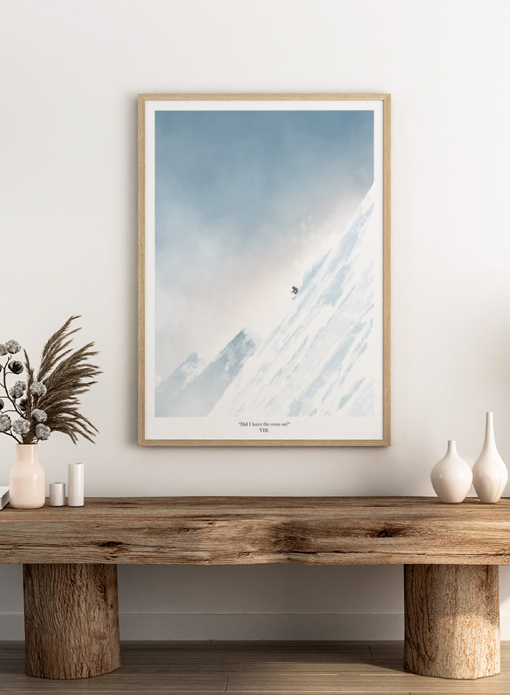 A framed art print featuring a minimalist illustration of a skier on a snowy mountain slope under a pale blue sky, with the text &