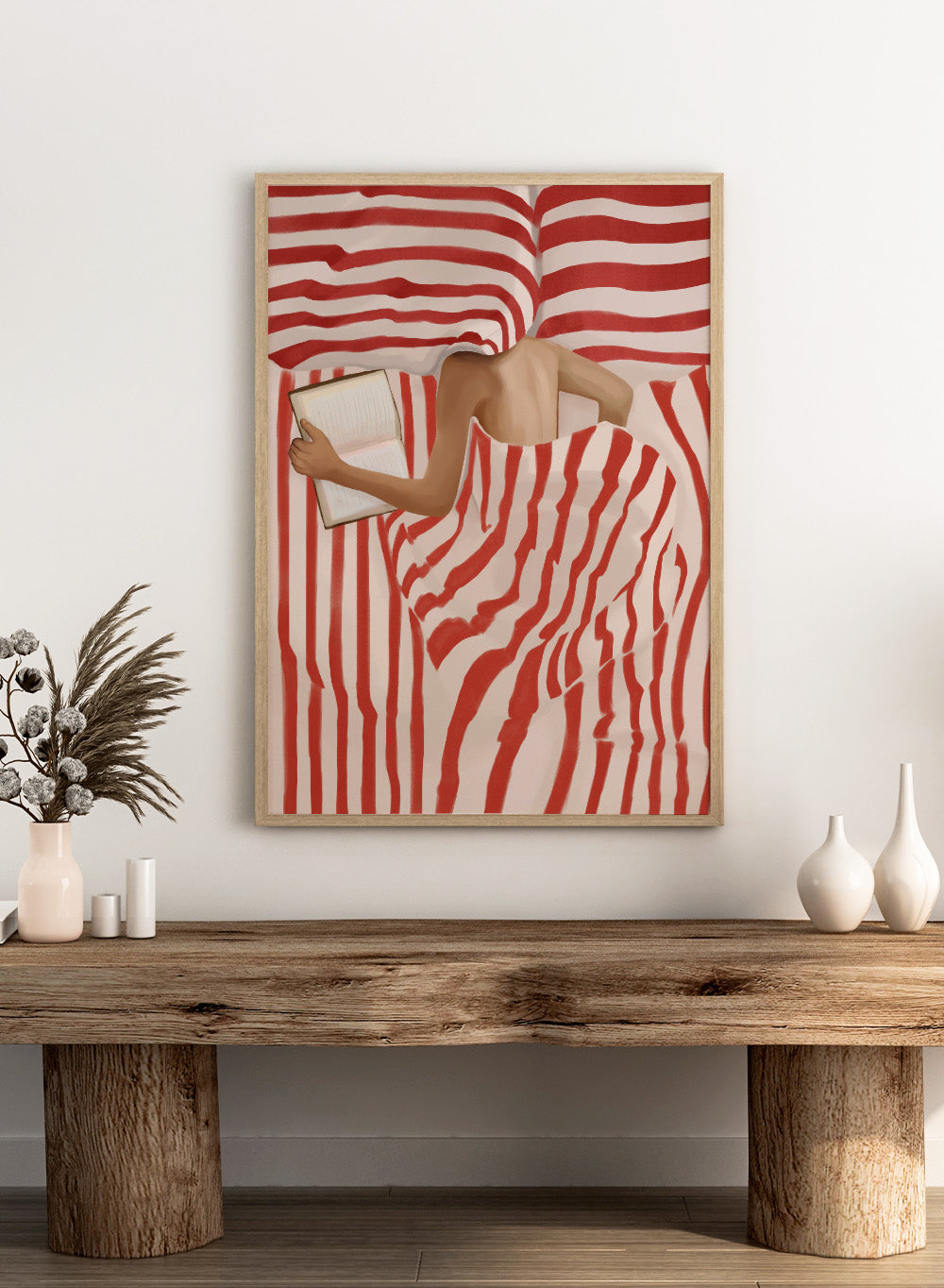 Between the Lines by Flow Line art print shows a woman reading in bed wrapped in red striped bedding. A modern lifestyle wall poster inspired by slow evenings.