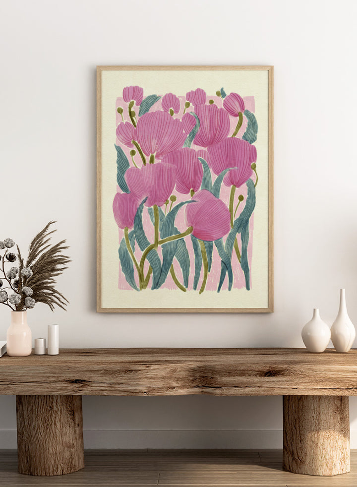 A framed art print featuring a stylized illustration of pink tulips with textured green leaves on a light cream background. Shop Pink Tulips by Katie O&