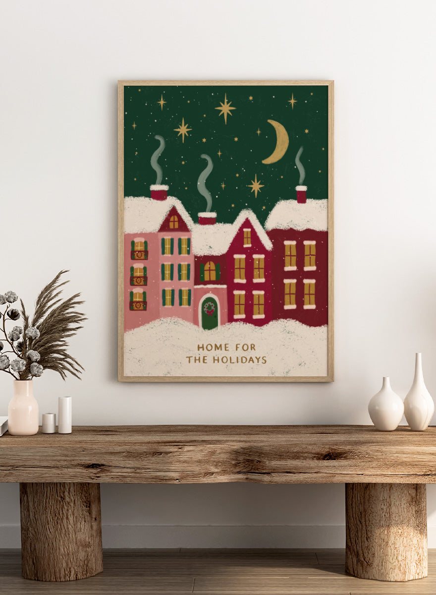Shop Home For The Holidays by Katarzyna Gąsiorowska, a Christmas wall art print poster featuring snowy houses, glowing windows, stars, and a cozy winter village scene.