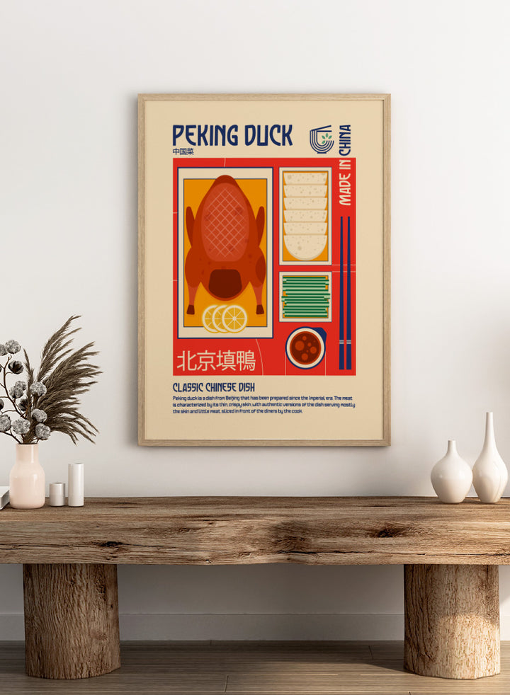 A stylized travel poster of Peking Duck, featuring a large illustration of a roasted duck, steamed buns, chopsticks, and a bowl of sauce on a beige background with red and blue graphic borders. Classic Peking Duck by Retrodrome retro kitchen art featuring Peking duck, pancakes, scallions, dipping sauce, Chinese typography, and bold vintage color.