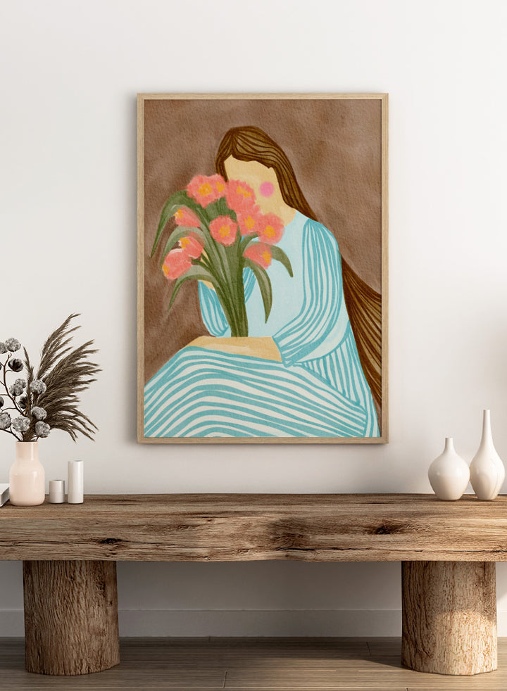 A stylized art print depicting a woman with long brown hair in a light blue striped dress holding a bouquet of pink tulips, set against a textured brown background. Shy Woman Pink Tulips by Nikita Jariwala, a figurative wall art print poster with pink tulips, blue dress illustration, and romantic floral decor.