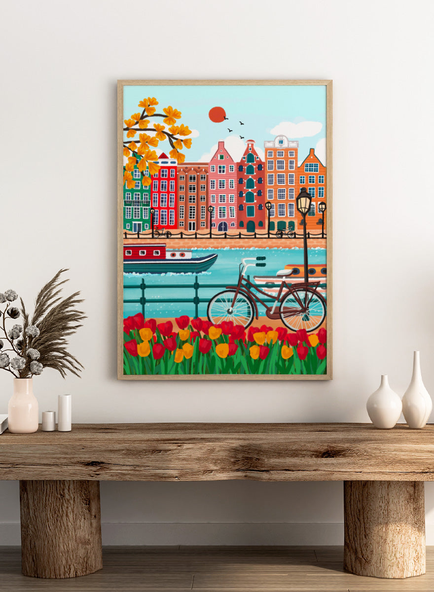 A colorful illustrated city canal scene with row houses, a bicycle, boats, flowers, and a bright sun.  Shop Colorful Amsterdam Canal by Nidhi Kachhadiya, a vibrant Amsterdam wall art print with canal houses, tulips, a bicycle, and colorful city charm.
