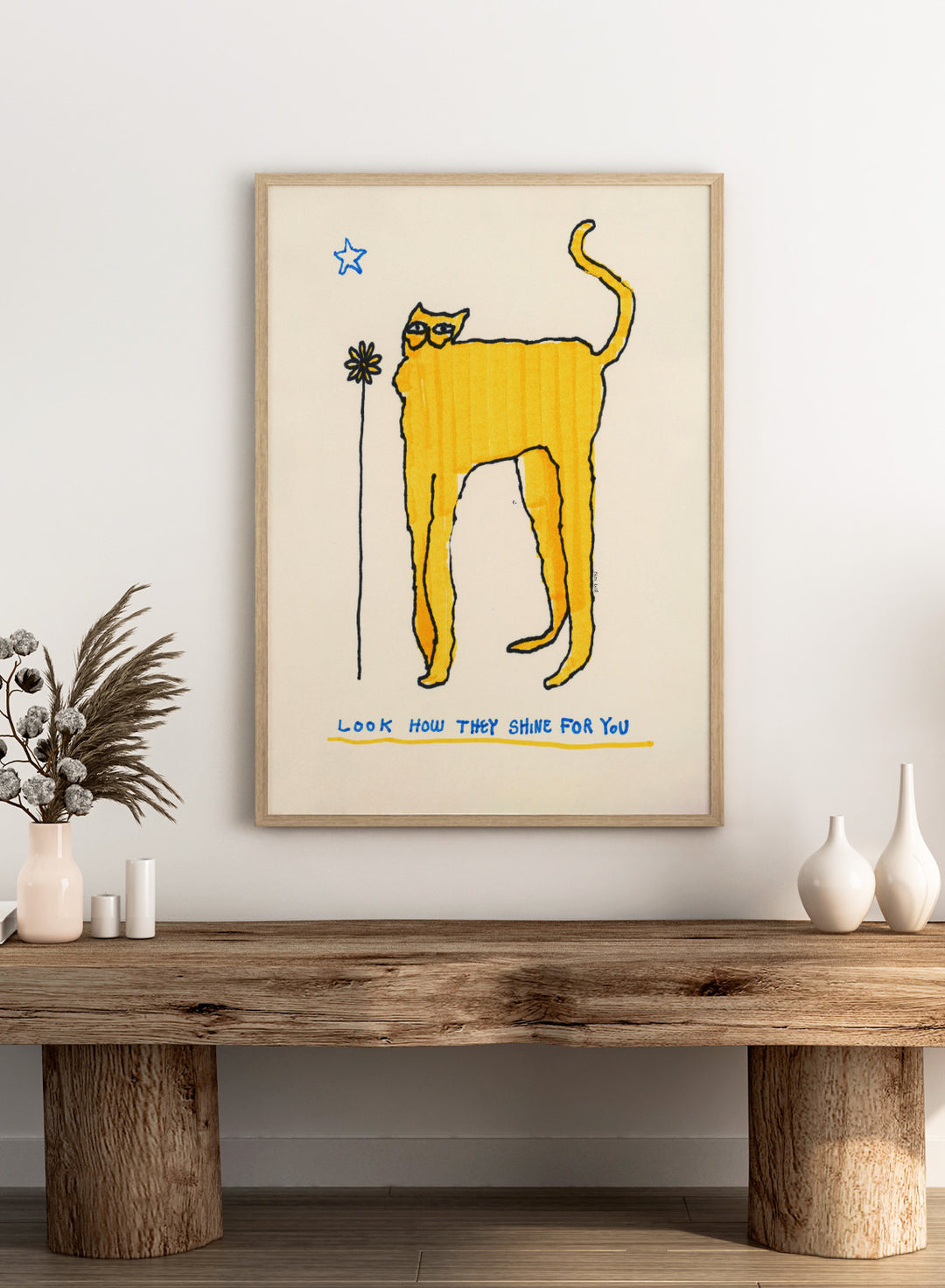 Yellow cat illustration with a flower and text on a beige background. Look How They Shine for You by Eden Kalif is a modern cat art print in yellow with text, a contemporary minimalist wall poster with playful form and expressive line work.