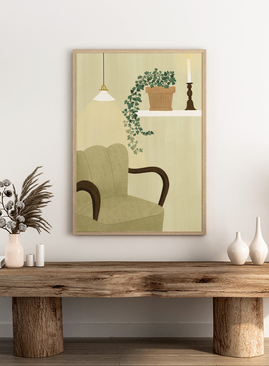A framed art print featuring a cozy interior scene with a beige armchair, a hanging pendant light, a shelf with a potted trailing green plant and a candlestick, and a cream-colored wall background. Shop Cozy Indoor Retreat by Elsa Nätterdal, a modern interior art print featuring a cozy armchair, trailing houseplant, candlelight, and warm neutral tones.