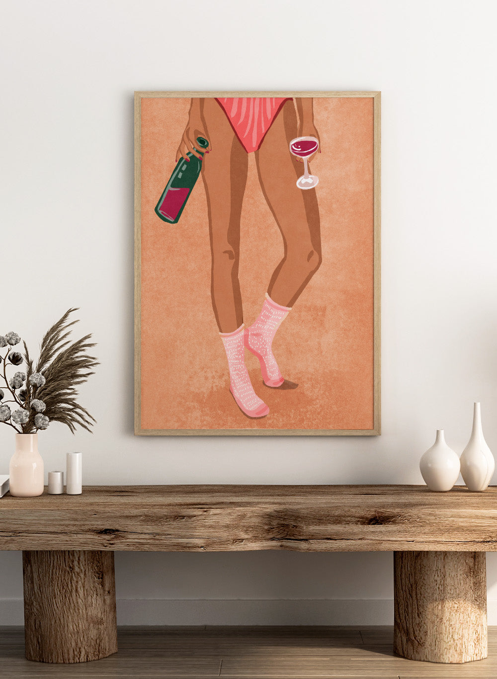 Illustration of a person's legs wearing pink socks with text, holding a bottle and a glass on a peach background. Wine and Socks by Raissa Oltmanns is a modern woman art print featuring wine bottle and glass in bold contemporary wall poster style.