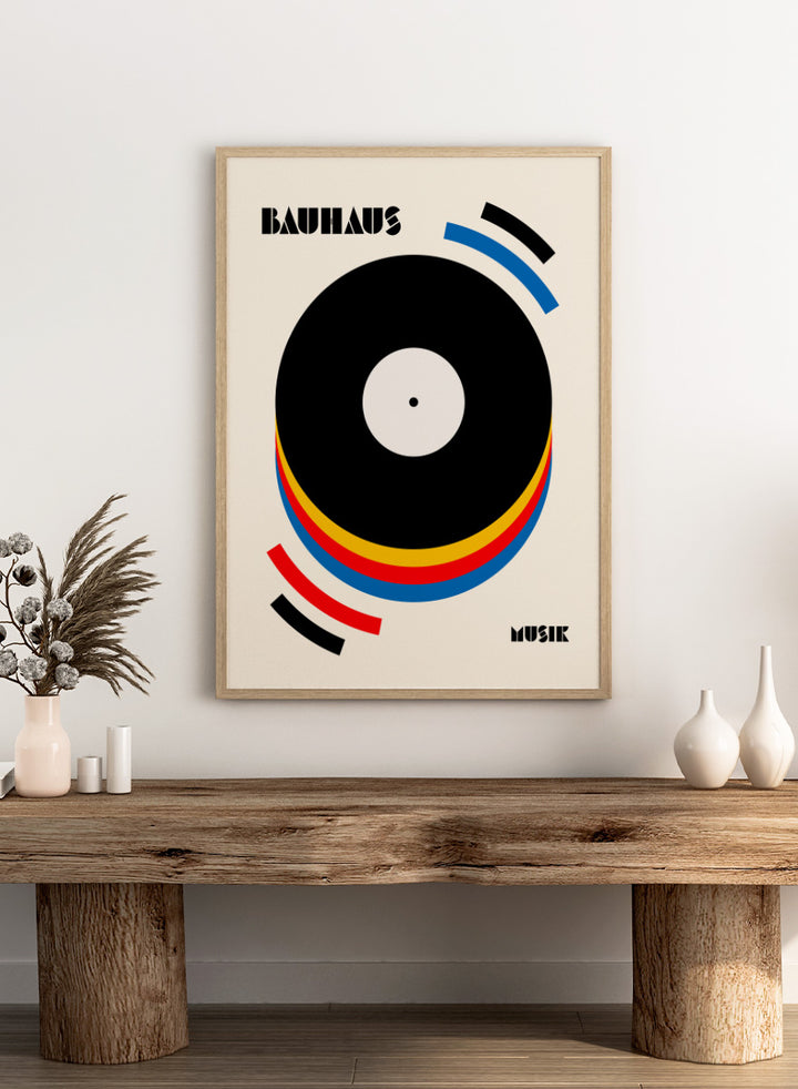A Bauhaus-style poster featuring a large black vinyl record graphic with concentric red, yellow, and blue rings on a warm cream background, with the words &