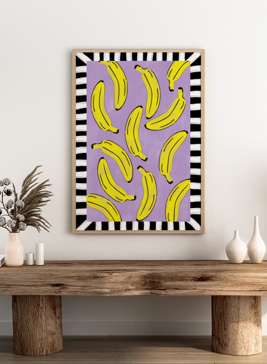 Shop Playful Banana Scatter by Elena Ristova, a banana wall art print poster in yellow, purple, black, and white with a bold striped border.