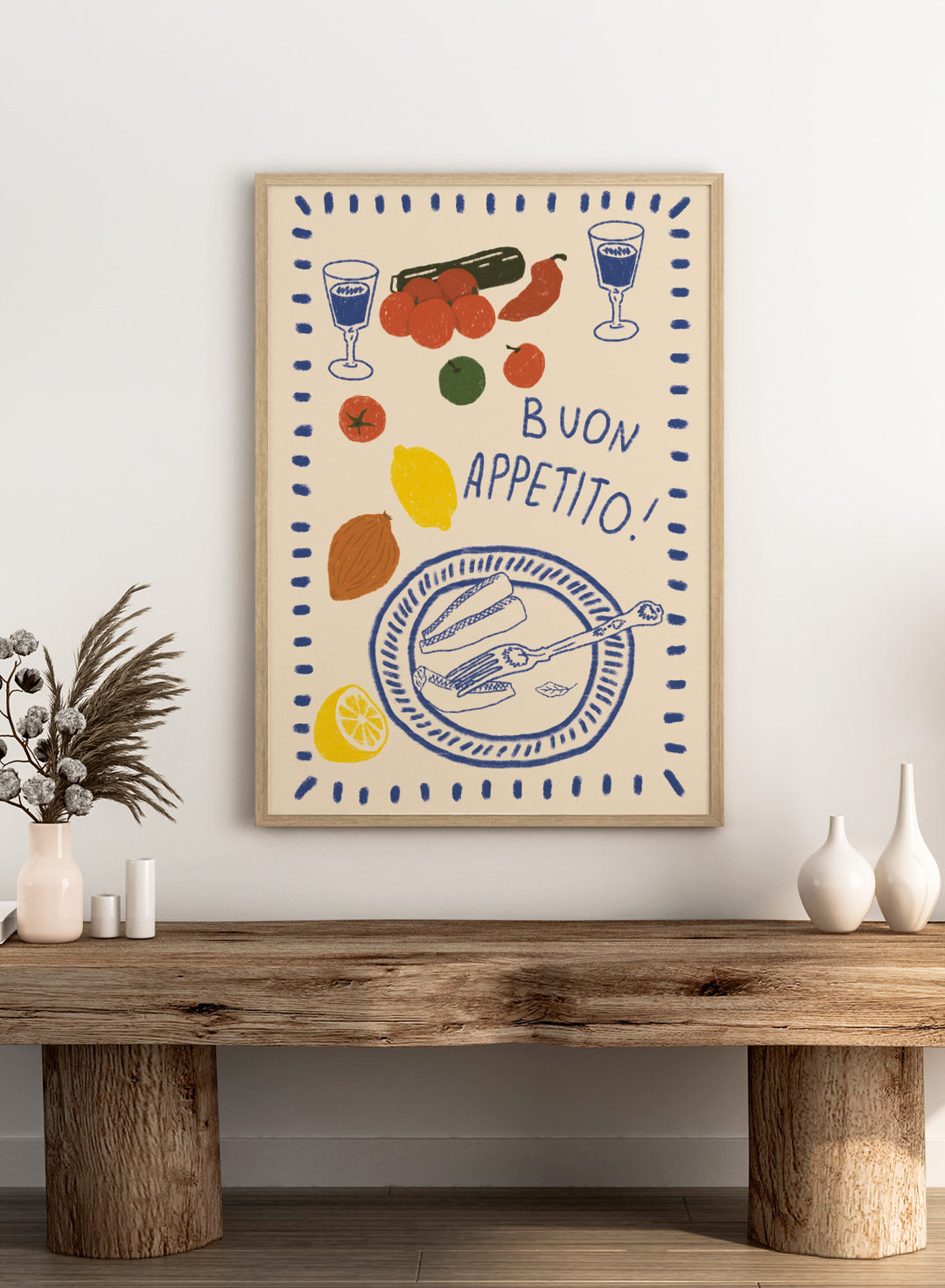 An illustrated print or card with the Italian phrase “BUON APPETITO!” in blue lettering, surrounded by hand-drawn food items including tomatoes, a lemon, an almond, a cucumber, a plate with bread and a fork, and two glasses with blue liquid. Buon Appetito Meal by Lisa Solomoniuk premium framed fine art print featuring a finished meal, wine glasses, fresh ingredients, and playful Italian lettering.