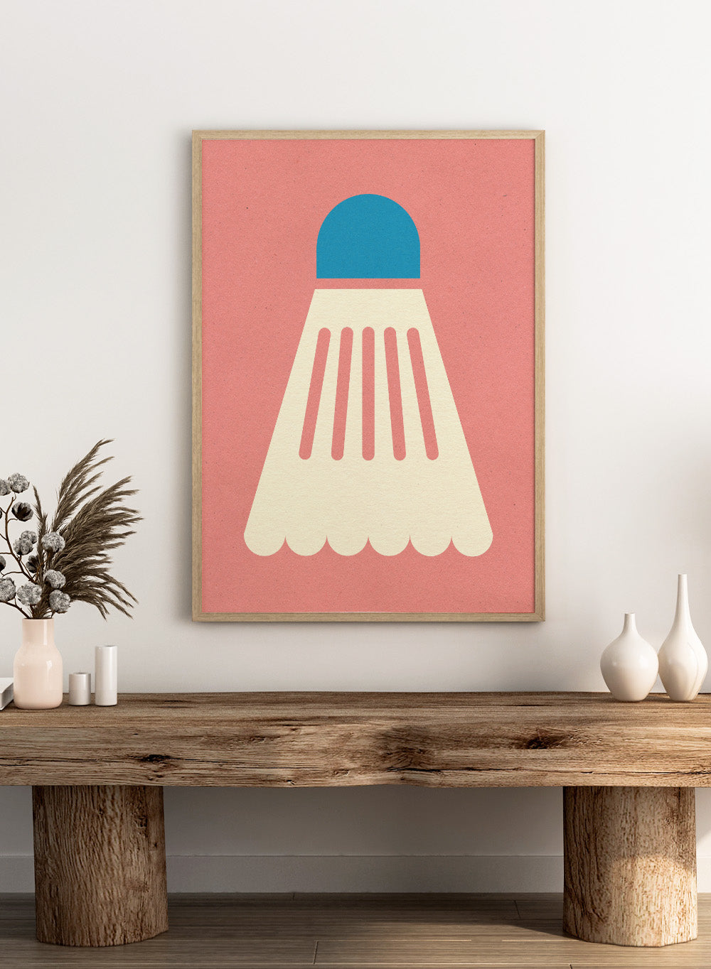 Shuttlecock with blue top and white body on a pink background. Badminton White Blue by Rosi Feist is a modern sports wall art print featuring a minimalist shuttlecock design in bold color and graphic poster style.