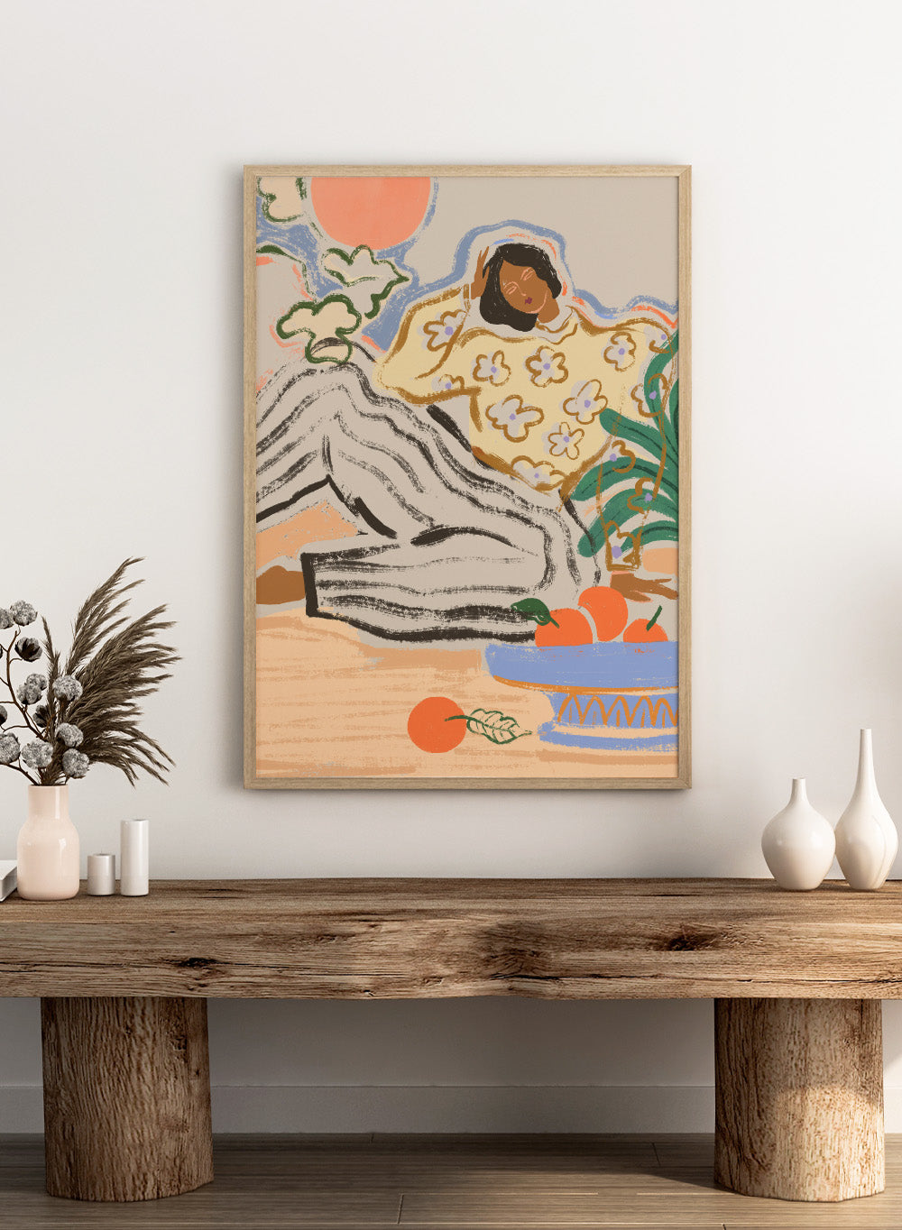 Artistic depiction of a person lounging on a beach with a bowl of fruit and flowers. Lazy Days by Arty Guava is a modern woman art print with warm colors, oranges, and relaxed still life details. Officially licensed wall poster.
