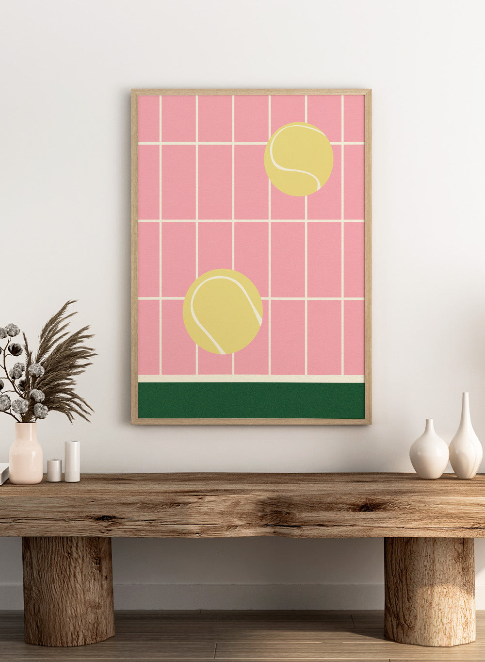 Two yellow tennis balls on a pink grid background with a green stripe at the bottom. Tennis Kitchen by Rosi Feist is a modern minimalist fine art print featuring oversized tennis balls on pink tile. Officially licensed wall poster with optional artisan framing.