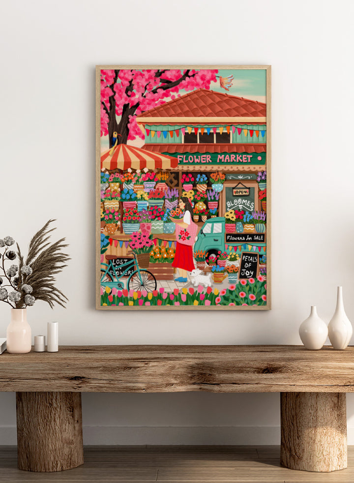 A colorful illustrated flower market scene with a shop front, blooming pink cherry blossoms, flower stalls, a woman standing by a bicycle, and signs reading &