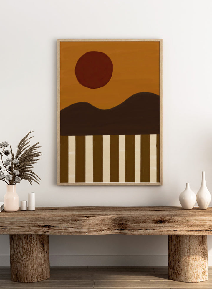A minimalist abstract landscape art print featuring a dark brown sun over a wavy horizon, with vertical brown and cream stripes at the bottom. Minimalist Desert Sun by The Art Concept landscape art print featuring a red sun, dark rolling hills, warm ochre tones, and bold vertical stripes.