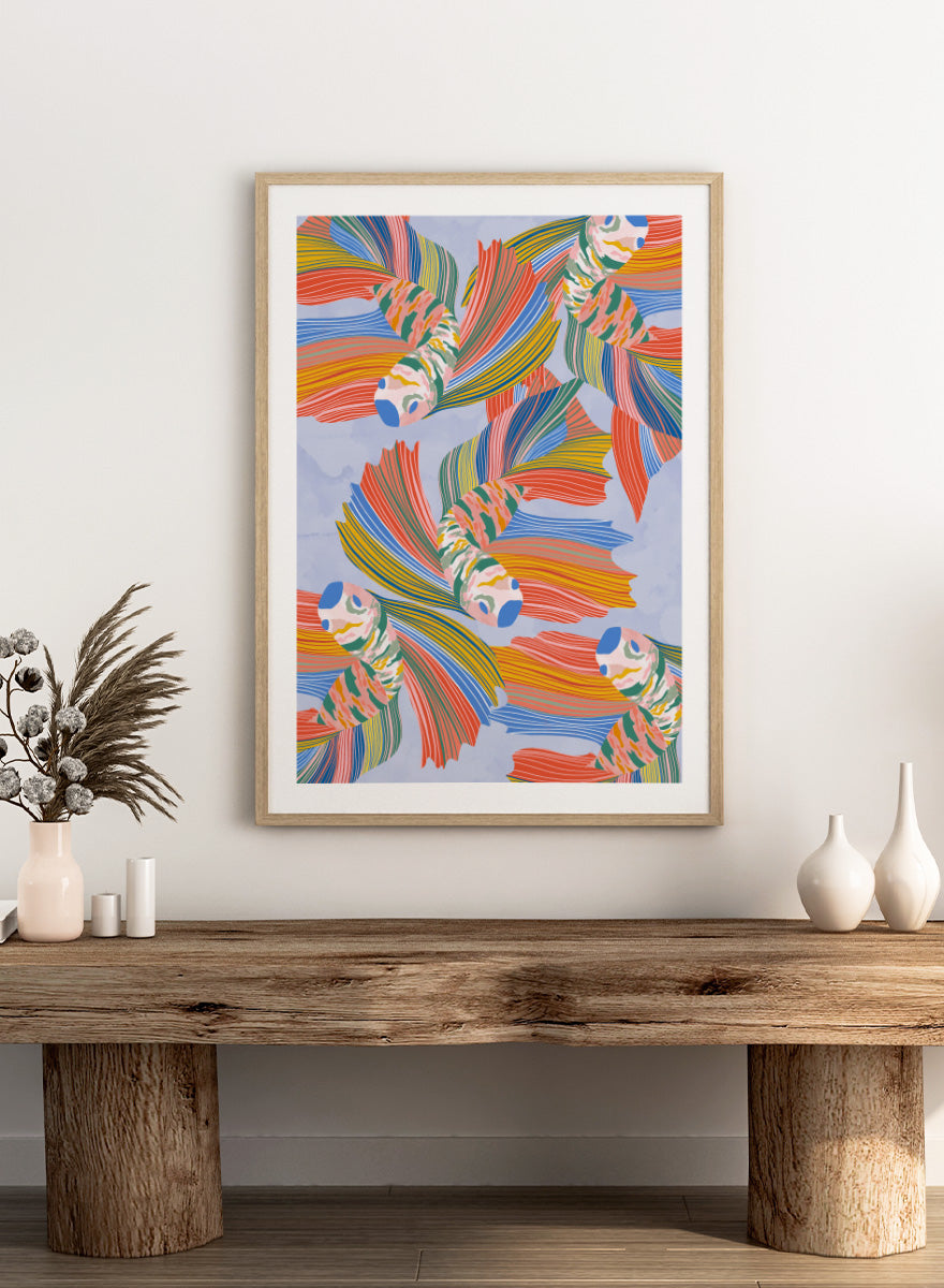 A framed art print featuring a colorful pattern of stylized fish with flowing striped fins in orange, yellow, green, blue, and red on a light blue background. Vibrant Swirling Fish Pattern by Ceyda Alasar art print featuring colorful flowing fish, striped fins, and playful aquatic movement on a soft blue background.