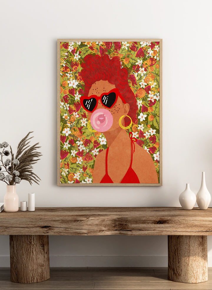 Illustration of a woman with red hair, sunglasses, and a pink bubble gum against a floral background. Strawberry Lady by Raissa Oltmanns fine art print featuring bold female portrait with strawberry background, modern colorful wall decor poster.