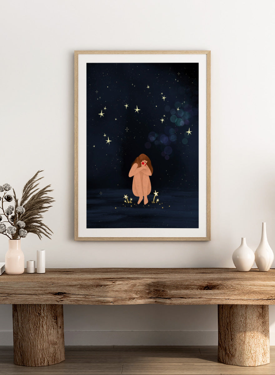 A framed art print featuring a whimsical illustration of a girl sitting on a dark blue starry night sky. Shop Starlit Solitude by Bea Müller, a figurative wall art print poster featuring a solitary woman beneath a star-filled night sky in deep blue tones.