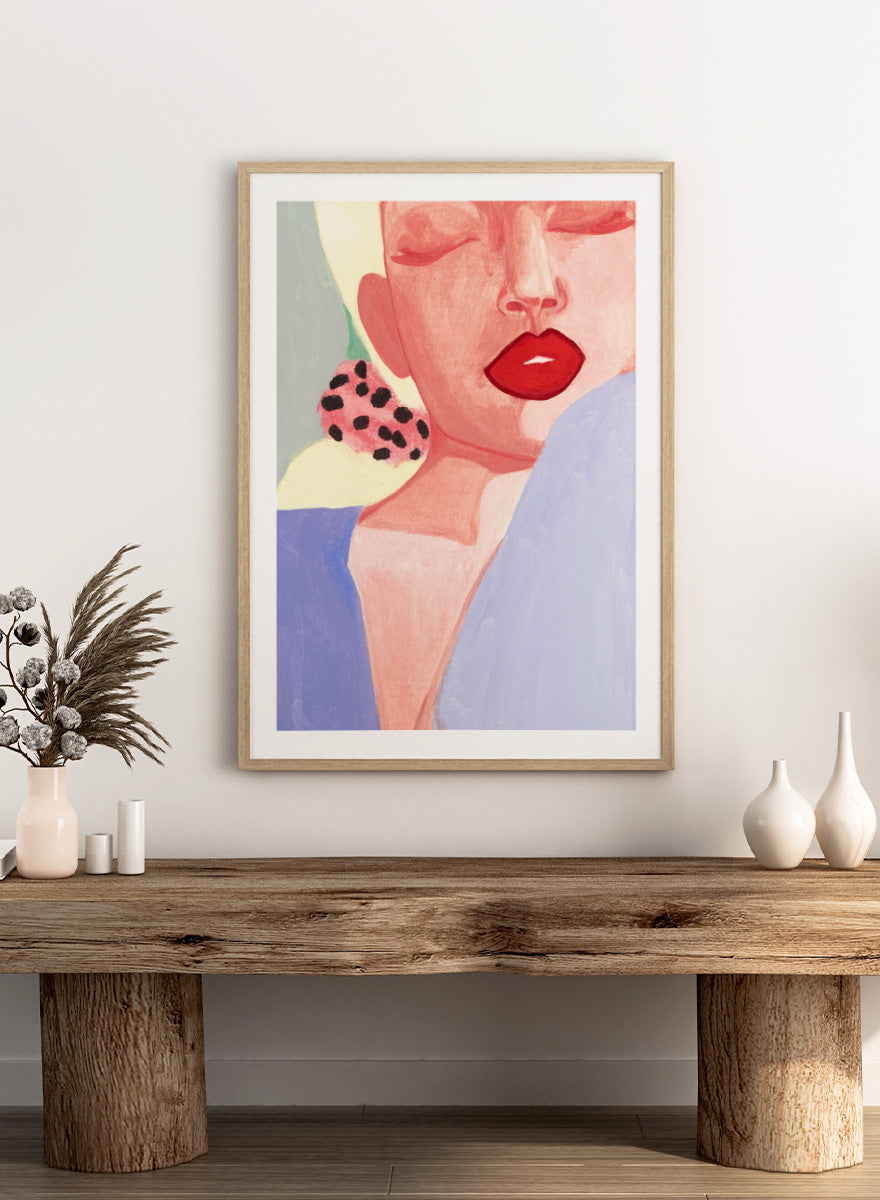Shop Red Lips by Sophia Novosel, a modern woman portrait wall art print poster featuring bold red lips, closed eyes, soft pink tones, and a spotted earring.