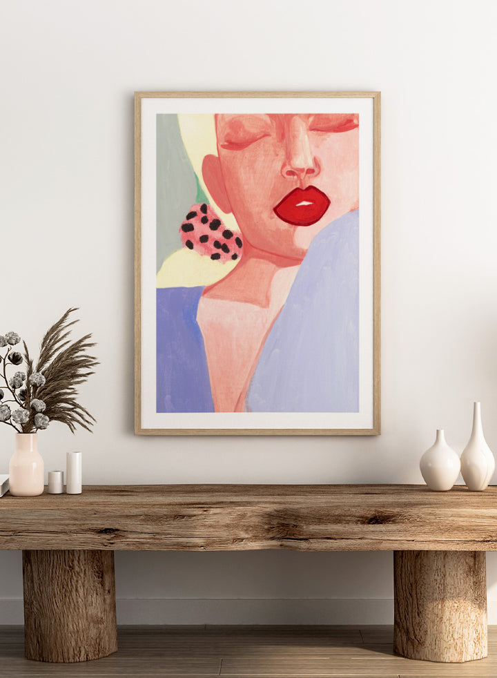 Shop Red Lips by Sophia Novosel, a modern woman portrait wall art print poster featuring bold red lips, closed eyes, soft pink tones, and a spotted earring.