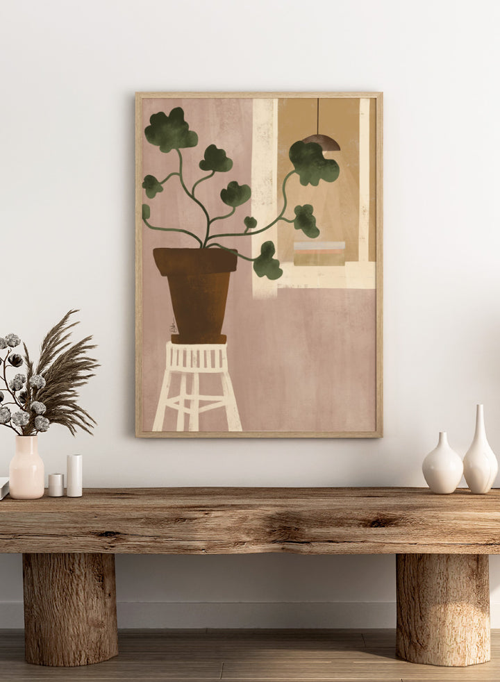 A minimalist art print depicting a potted green plant on a white stool against a dusty pink wall, with a window and hanging lamp in the background. Shop Cozy Houseplant Window by Elsa Nätterdal, a modern botanical interior art print featuring a leafy plant, soft neutral tones, and a cozy home setting.
