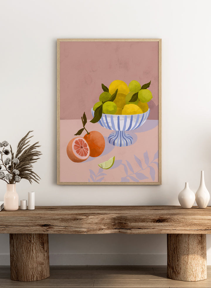 Illustration of a bowl with lemons and limes on a pink background. Bittersweet by Goed Blauw is a still life art print and wall poster with lemons, limes, and grapefruit in a striped bowl on a soft pink background.