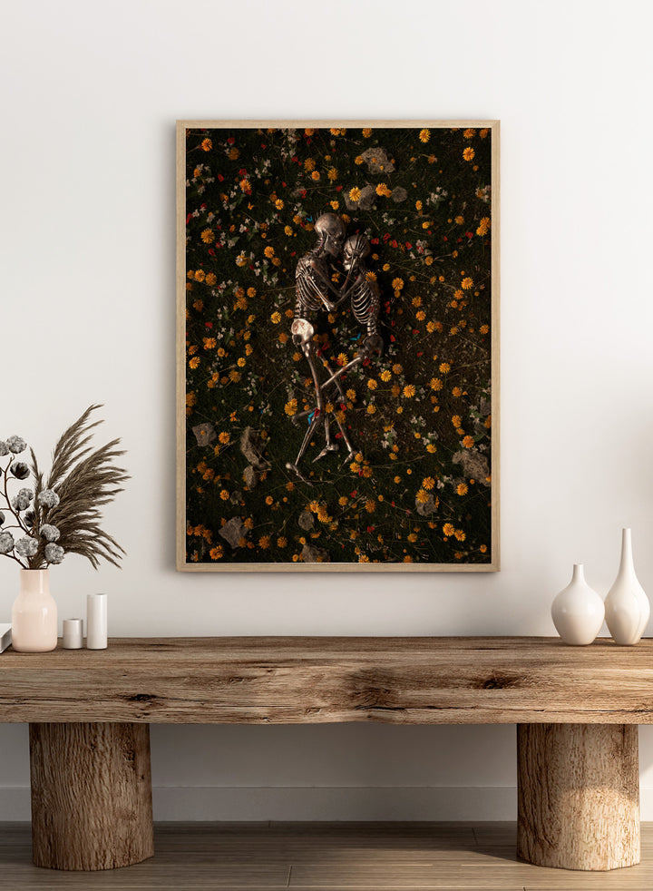 Skeletons In Love by Nicebleed is a surreal skeleton couple art print featuring intertwined skeletons in a floral field, modern aesthetic wall poster.