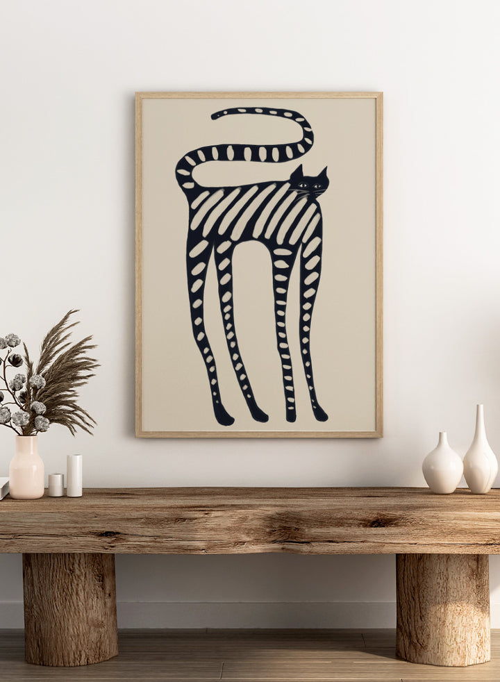A stylized black cat illustration with bold diagonal stripes and white oval spots on a warm beige background. Striped Whimsical Cat by The Art Concept playful cat art print featuring an elongated black cat with cream stripes and an oversized looping tail.