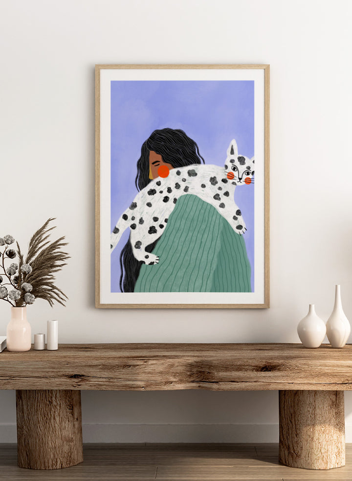 A framed art print featuring a stylized illustration of a woman with long black hair carrying a white cat with black spots over her shoulder, set against a lavender background. Woman and Spotted Cat by Bea Müller animal art print featuring a woman carrying a playful spotted cat, perfect for modern cat lover and pet decor.