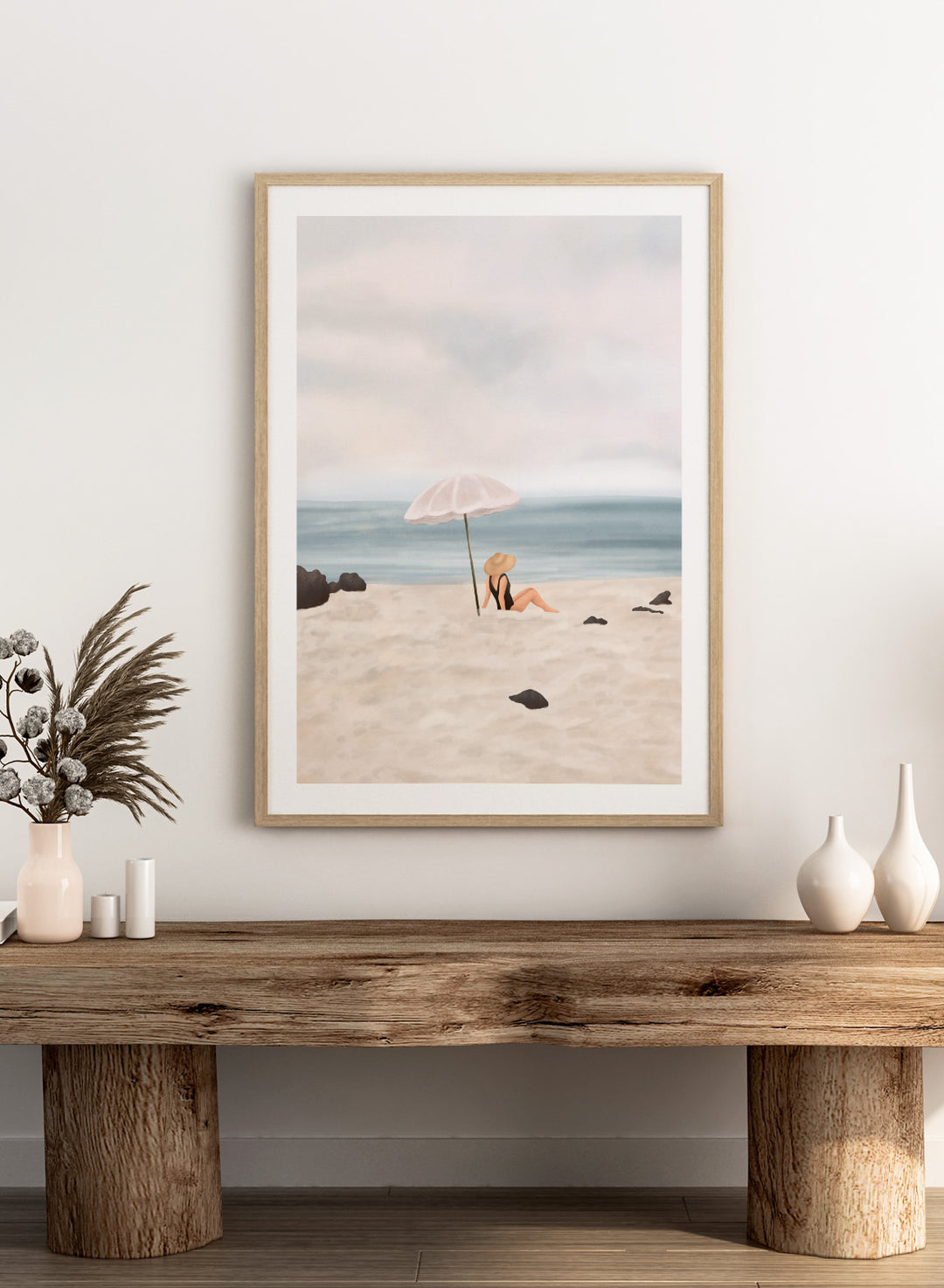Woman under an umbrella on a beach with a calm ocean and sky. Serene Beach Scene by Flow Line is a coastal art print featuring a woman by the ocean, beach umbrella, seaside illustration, and summer wall art.