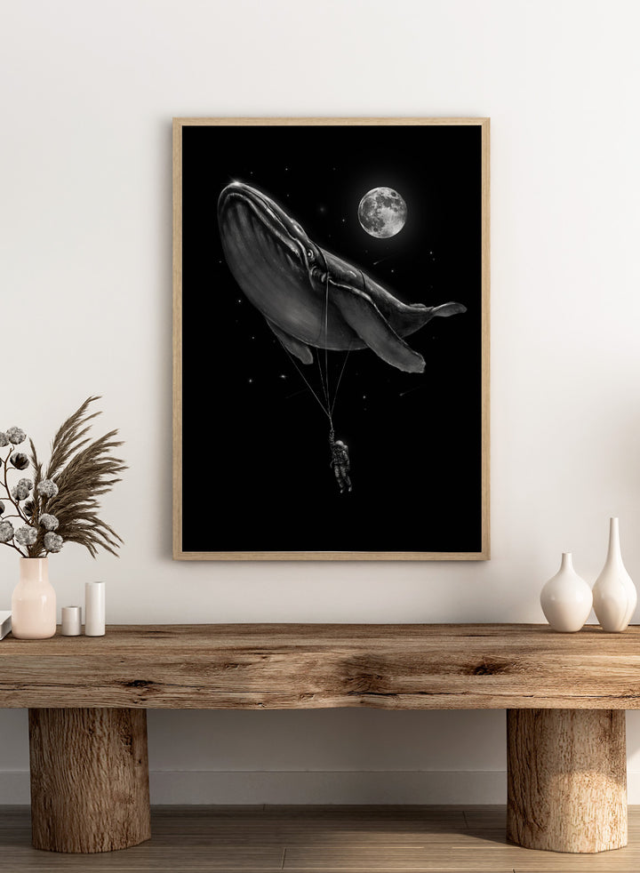 Black and white illustration of a large whale balloon with a person attached, set against a starry night sky with a moon. Cosmic Whale Ride by Nicebleed is a surreal space art print featuring an astronaut hanging from a floating whale, modern aesthetic wall poster.