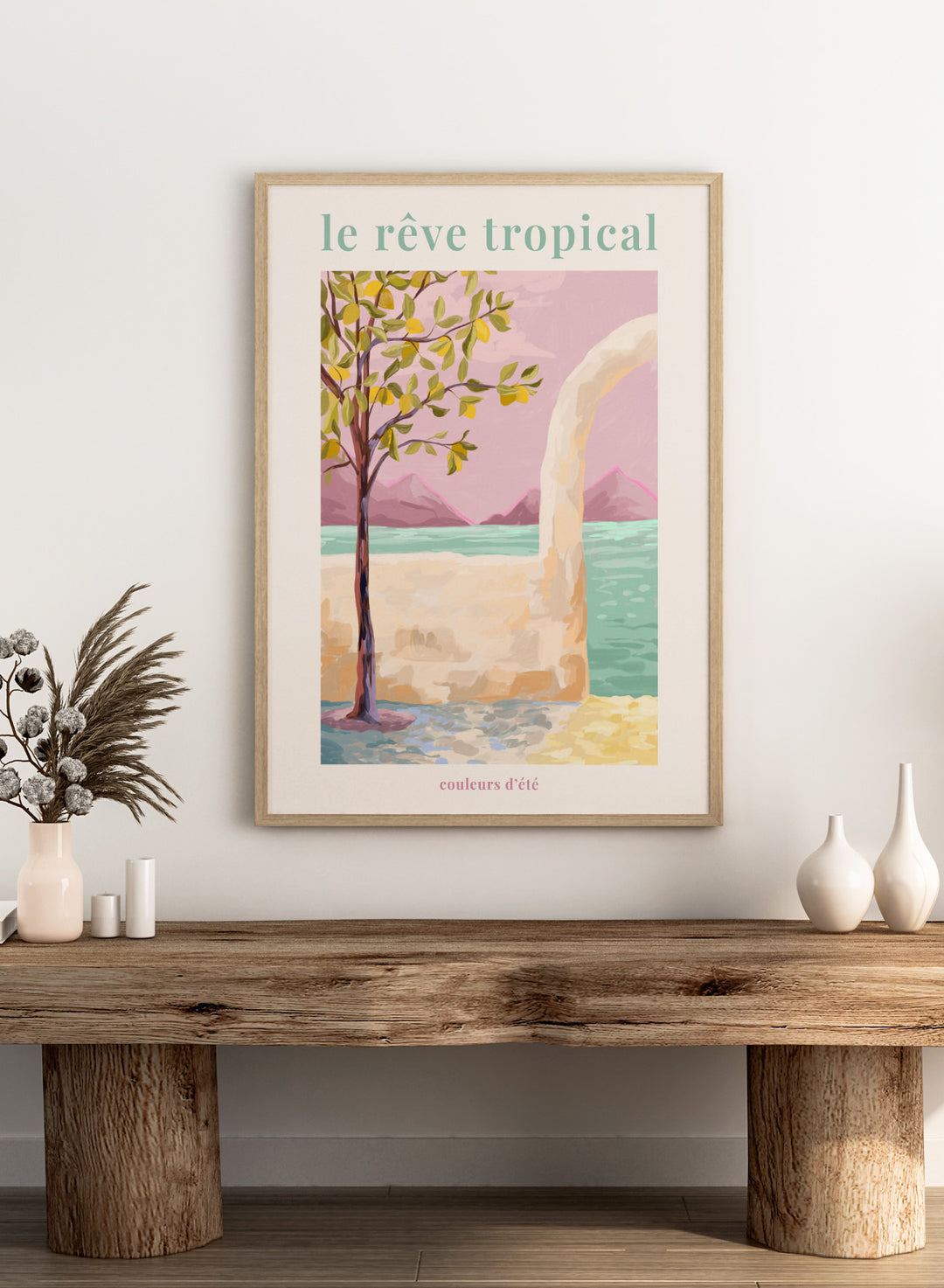 Artistic depiction of a tropical scene with a tree, beach, and mountains, featuring the text 'le rève tropical' and 'couleurs d'été'. Le Rêve Tropical Lemon Tree by Goed Blauw is a coastal art print and wall poster featuring a lemon tree, archway, and ocean view in warm pastel tones.