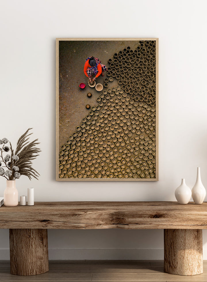 Person working with clay pots on a textured surface. Pot Making by Azim Khan Ronnie aerial photography print showing clay pots drying in Bangladesh village, traditional craft wall art poster
