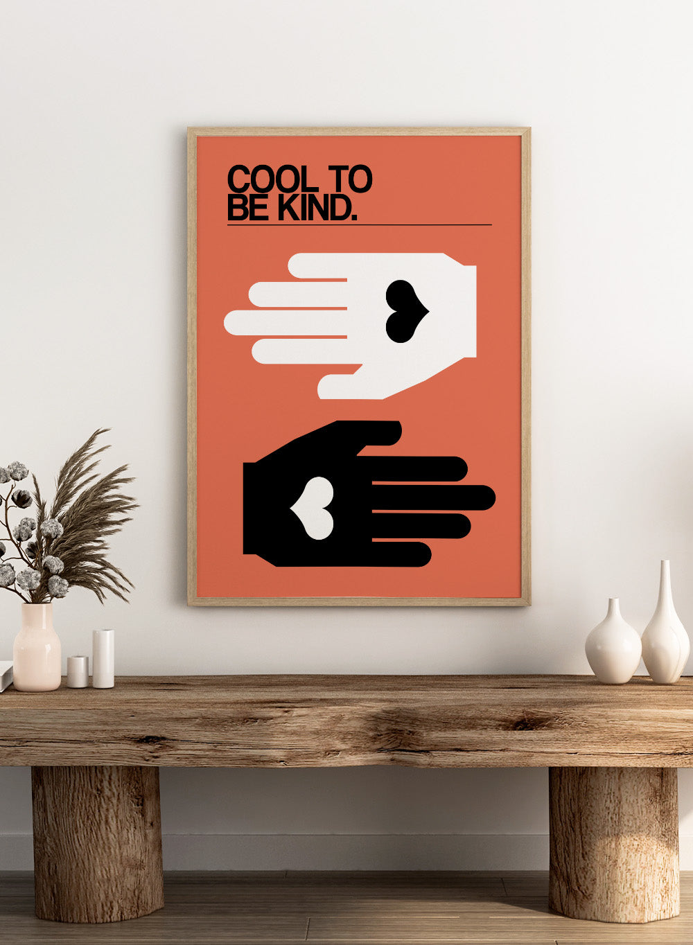 Poster with two hands reaching towards each other, one white and one black, on an orange background with 'Cool to be kind' text. Cool To Be Kind by Frances Collett is a modern kindness art print featuring two graphic hands with heart symbols. Officially licensed contemporary wall poster with optional framing.